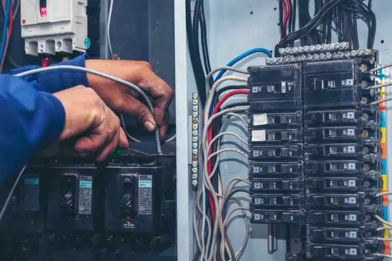 Electricista conectando cables en un tablero con breakers